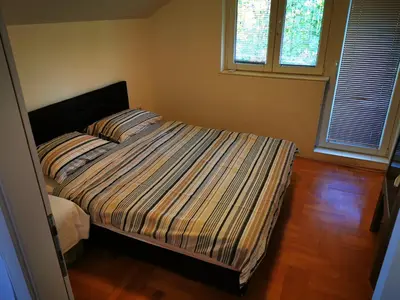 a bedroom with a bed with a striped comforter and a window at Sokobanja central park APT with mountain view balcony in Soko Banja