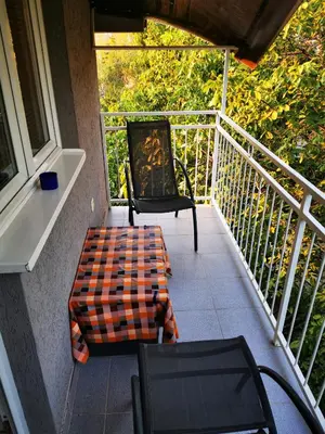 a porch with two chairs and a suitcase on a balcony at Sokobanja central park APT with mountain view balcony in Soko Banja