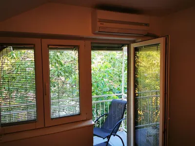 a room with three windows and a chair on a balcony at Sokobanja central park APT with mountain view balcony in Soko Banja