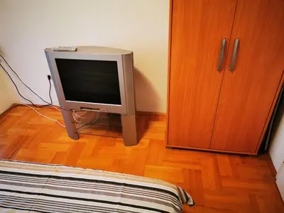 a television sitting on a wooden floor next to a cabinet at Sokobanja central park APT with mountain view balcony in Soko Banja