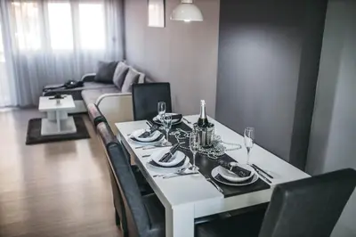 a dining room table with chairs and a white table and chairsktop at King Exclusive Suites in Niš