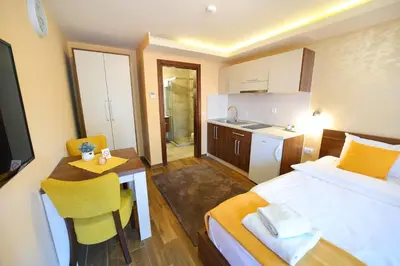 a hotel room with a bed and a table and a kitchen at Vila Almax in Soko Banja