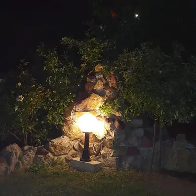 a lamp in front of a stone wall at night at Knez Apartmani in Senje