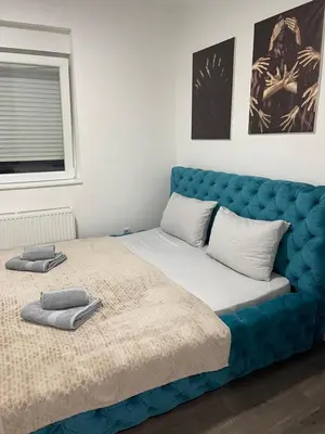 a bed with a blue headboard in a room at La Apartamento in Jagodina
