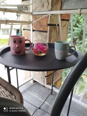 a table with two cups and a bowl of flowers at Apartmani Marić In in Vrnjačka Banja