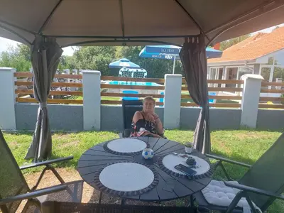 a woman sitting at a table in a gazebo at Vila Boba Bor in Zlot