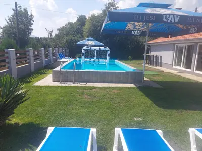 a pool with an umbrella and chairs and a swimming pool at Vila Boba Bor in Zlot