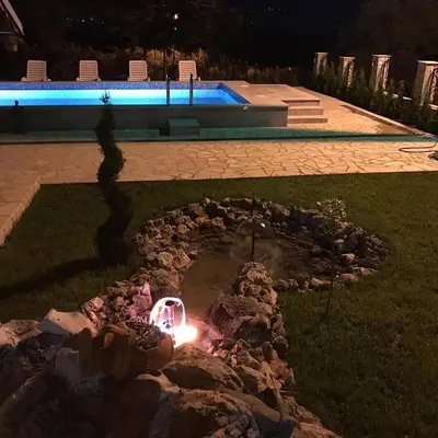 a pond in a yard at night with a candle at Apartmani Djokić sa bazenom in Soko Banja