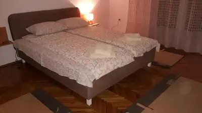 a bedroom with a bed with a wooden floor at Apartman Lela in Vranje