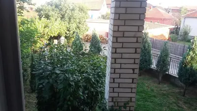 a garden with a fence and a brick pillar at Apartman Lela in Vranje