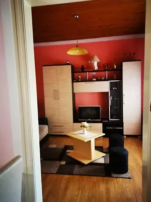 a living room with a table and a red wall at Apartman Luka in Soko Banja