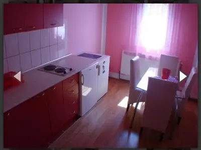 a kitchen with pink walls and a table with chairs at Apartman Luka in Soko Banja