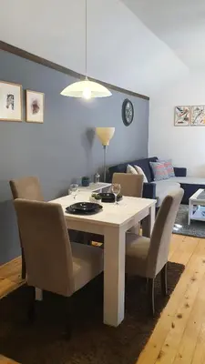 a white dining room table with chairs and a couch at Kum Apartment in Niš