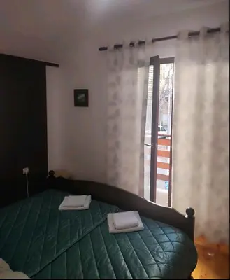 a bedroom with a green bed with two towels on it at Kum Apartment in Niš