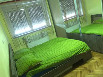 two twin beds in a room with two windows at Tanja apartman in Jagodina