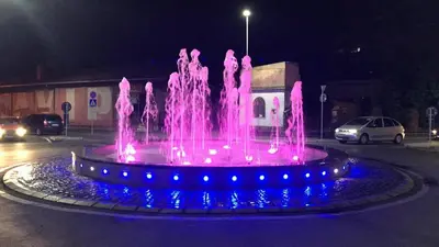 a pink fountain with blue lights in a parking lot at Tanja apartman in Jagodina