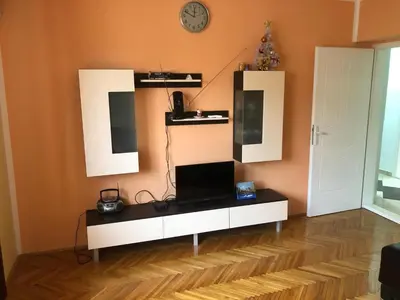 a living room with a white cabinet and a clock at Tanja apartman in Jagodina