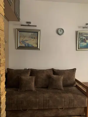 a couch in a living room with a clock on the wall at Eco Kop in Kopaonik
