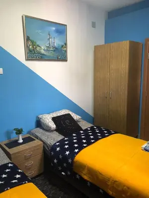 a bedroom with two beds and a painting on the wall at Swiss Hostel in Kruševac