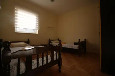 a bedroom with two beds and a window with blinds at Hostel Teresianum in Aleksinac
