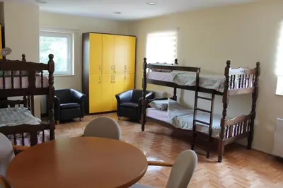 a room with two bunk beds and a table and chairs at Hostel Teresianum in Aleksinac