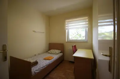 a small bedroom with a bed and a window at Hostel Teresianum in Aleksinac