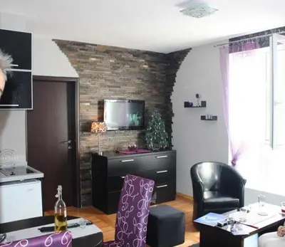 a living room with a tv on a brick wall at Lila Apartman u Kraljevim Čardacima in Kopaonik