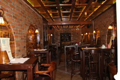 a restaurant with brick walls and wooden tables and chairs at Lila Apartman u Kraljevim Čardacima in Kopaonik