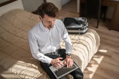 a man sitting on a couch using a laptop computer at Garni Hotel 018 In in Niš