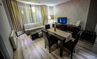 a living room with a dining room table and a television at Garni Hotel 018 In in Niš