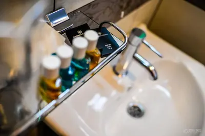 a bathroom sink with a mirror and bottles on it at Garni Hotel 018 In in Niš
