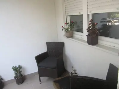 a room with a chair and two windows with potted plants at River View Nis - 65 square meters Designer Apartment in heart of city Park for free in Niš