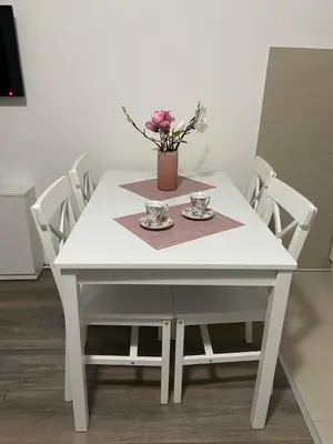 a white table with a vase of flowers on it at Apartman Aleksic in Jagodina