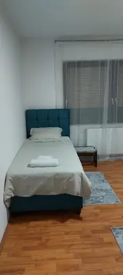 a bedroom with a bed with a blue head board at Apartman Aleksic in Jagodina