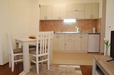 a kitchen with white cabinets and a table and chairs at Apartman Nensy in Vrnjačka Banja
