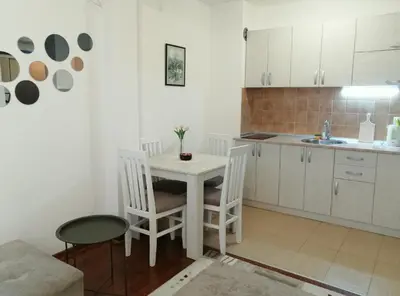 a kitchen with a white table and chairs in a room at Apartman Nensy in Vrnjačka Banja