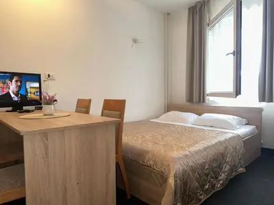 a hotel room with a bed and a desk with a television at Apartman Masa Kopaonik in Kopaonik