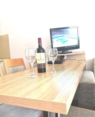 a bottle of wine and two wine glasses on a wooden table at Apartman Masa Kopaonik in Kopaonik