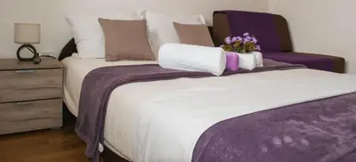 a bedroom with a bed with purple sheets and flowers on it at Apartman Soko in Soko Banja