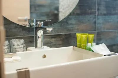 a bathroom sink with a faucet and a mirror at Hotel Aloha in Niš