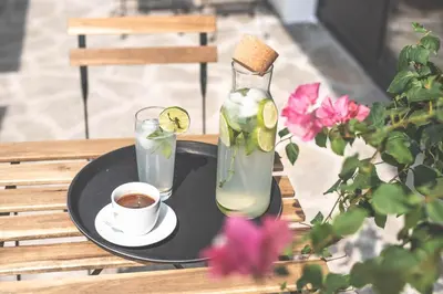 a table with a bottle and a cup of coffee and a drink at Hotel Aloha in Niš