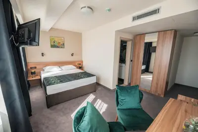 a bedroom with a bed and a television and a table at Hotel Aloha in Niš