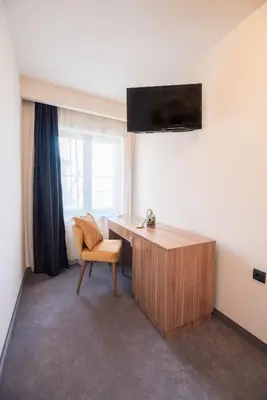 a room with a desk and a chair and a window at Hotel Aloha in Niš