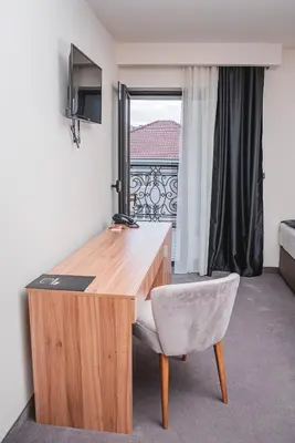 a desk and a chair in a room with a window at Hotel Aloha in Niš