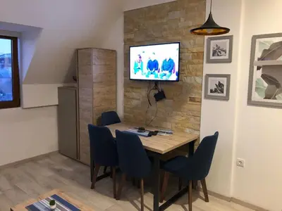 a dining room table with chairs and a tv on a brick wall at Kopaonik Milmari apartman L33 in Kopaonik
