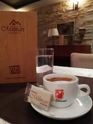 a cup of coffee and a glass of water on a table at Kopaonik Milmari apartman L33 in Kopaonik