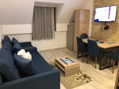 a living room with a blue couch and a table at Kopaonik Milmari apartman L33 in Kopaonik