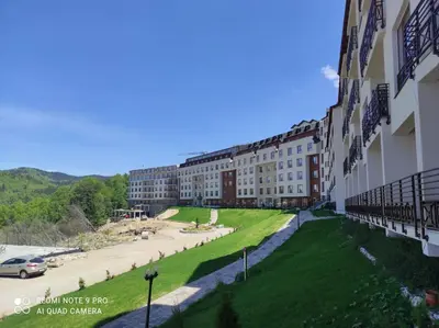 a building with a green lawn in front of it at Kopaonik Milmari apartman L33 in Kopaonik
