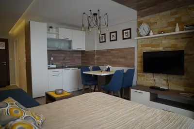 a bedroom with a bed and a kitchen with a table at Premier 24 Milmari Kopaonik in Kopaonik