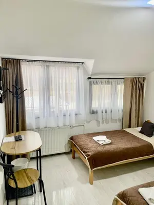 a bedroom with a bed and a table and windows at Kapija Svrljiga in Svrljig